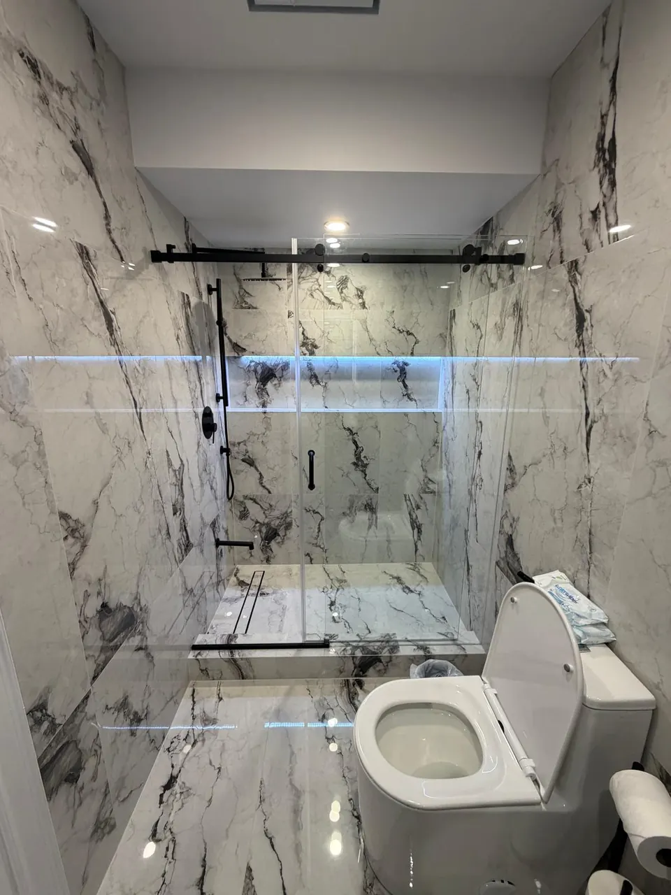 Sliding glass shower with LED shelf and marble-look walls